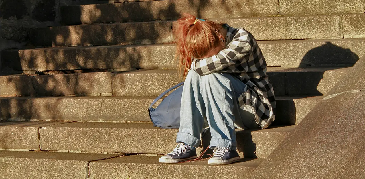 A young woman sits on the steps in sadness and despair, we can respond with hope when the world is full of tragedy